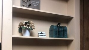 A shelf with a potted plant, a vintage mailbox, a wooden sign, and a crate. - All-inclusive Apartment - 1 Bedroom, 1 Bath, Equipped Kitchen, & Laundry (Terre Haute)