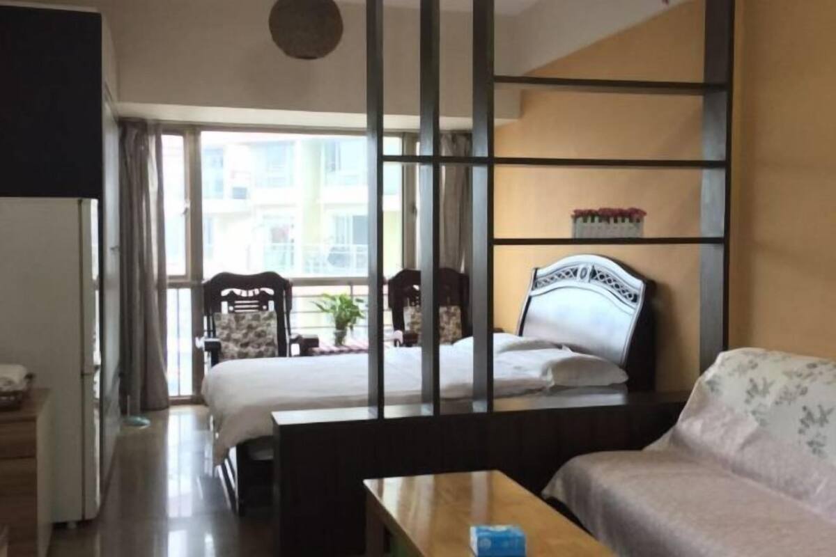 A hotel room with a bed, a sofa, a desk, and a large window.