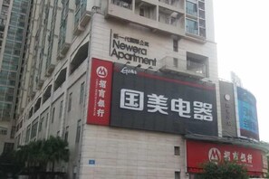 Un immeuble avec une enseigne indiquant « Newera Apartment » et un grand panneau publicitaire numérique faisant la promotion de « Guomei Electrical Appliances ».