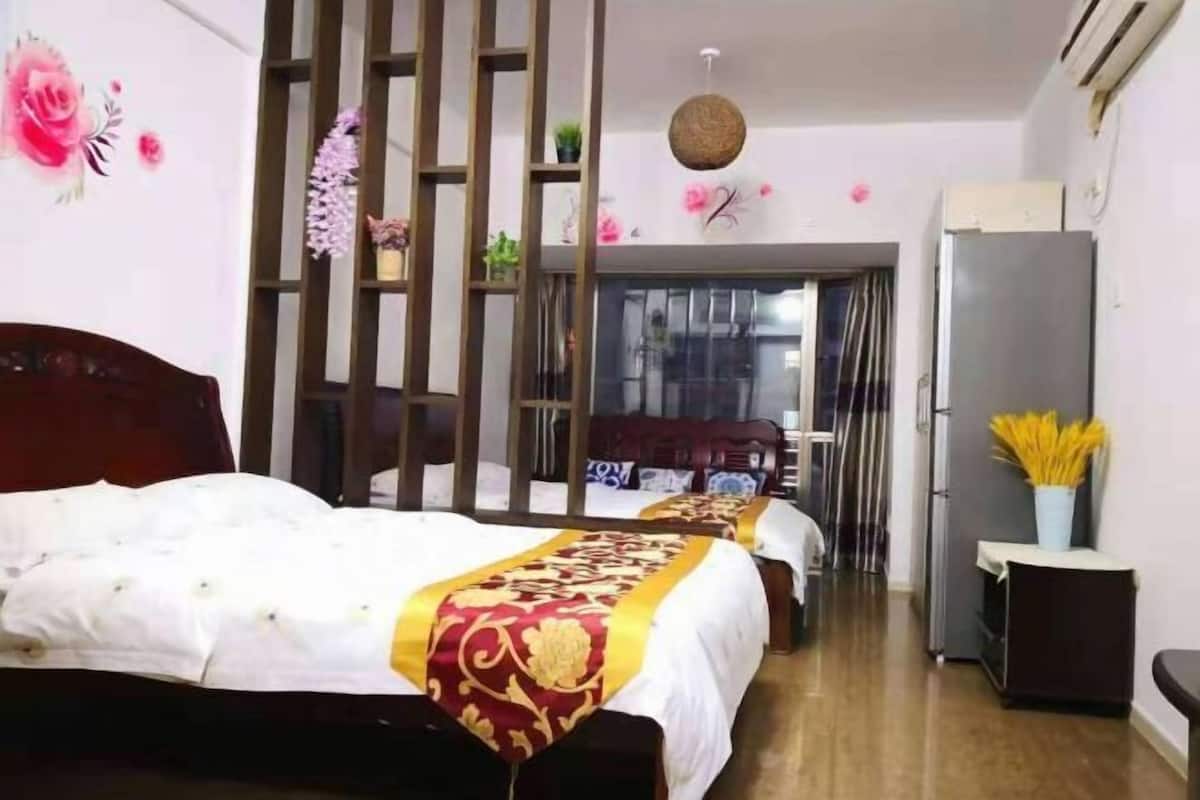 A hotel room with a large bed, a wardrobe, a desk, and a refrigerator.