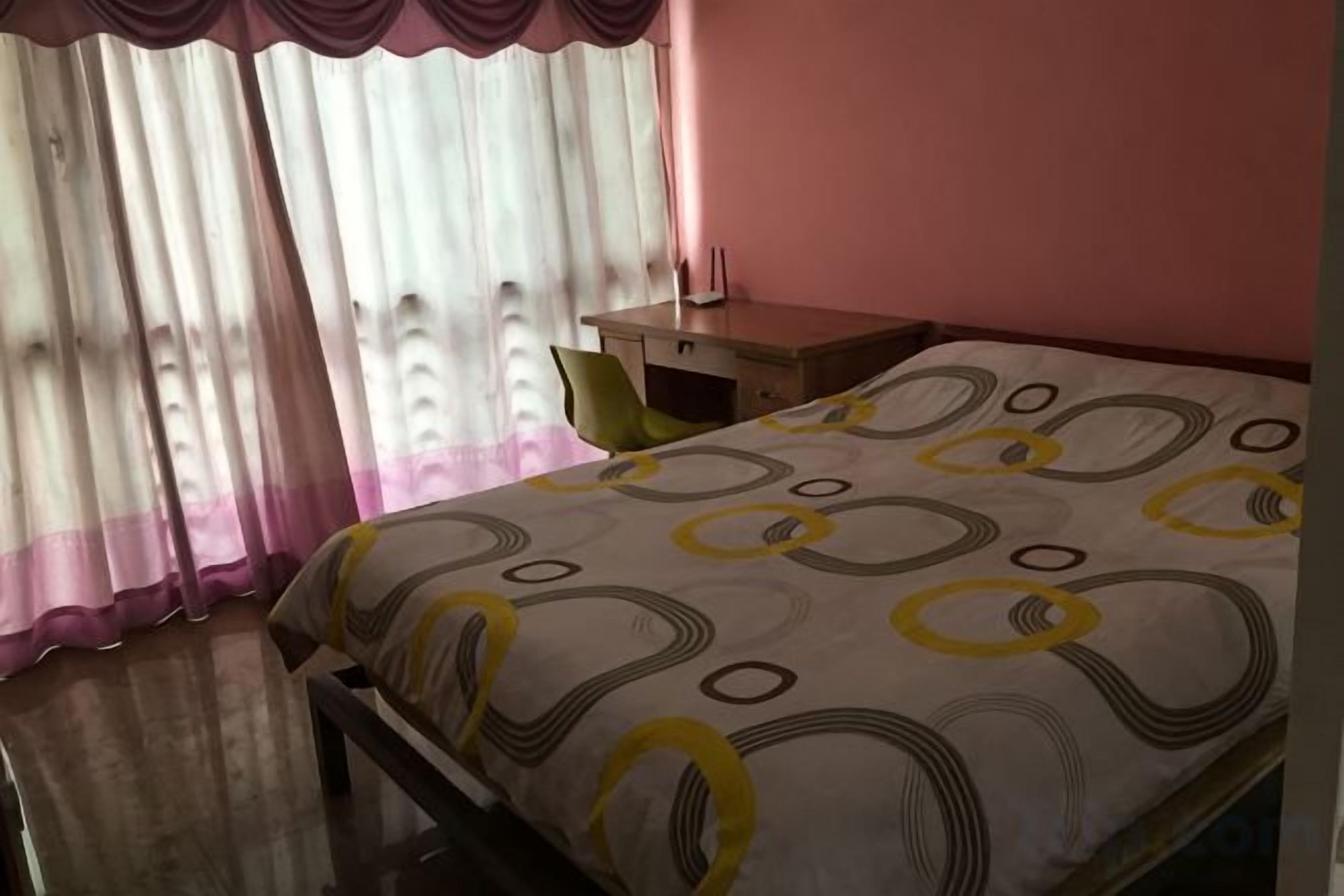 A bedroom with a bed, a nightstand, and a window with curtains.