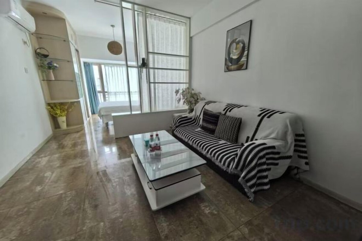 A modern living room with a sofa, a coffee table, and a large window.