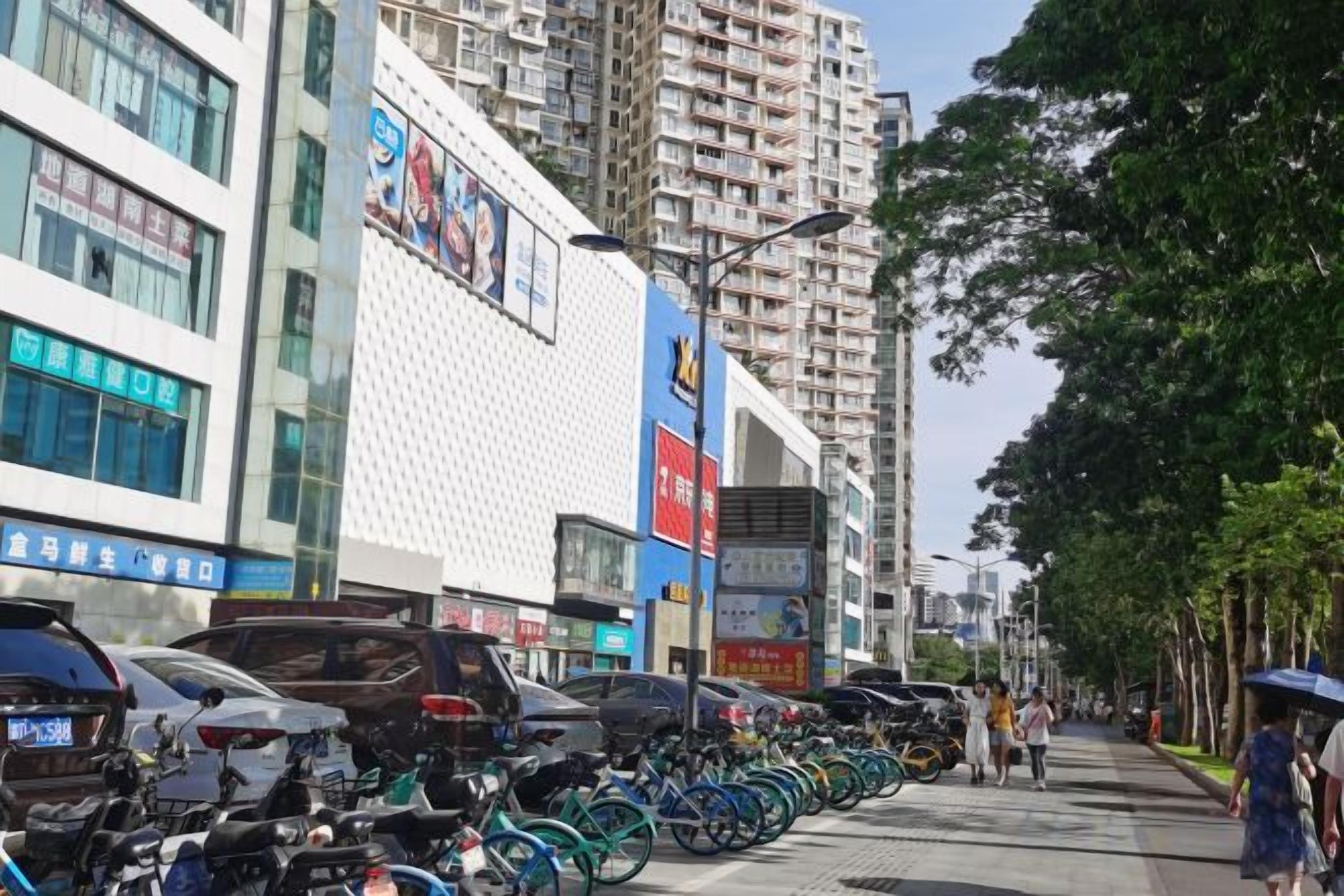 A street lined with parked bicycles and tall buildings with commercial signage.