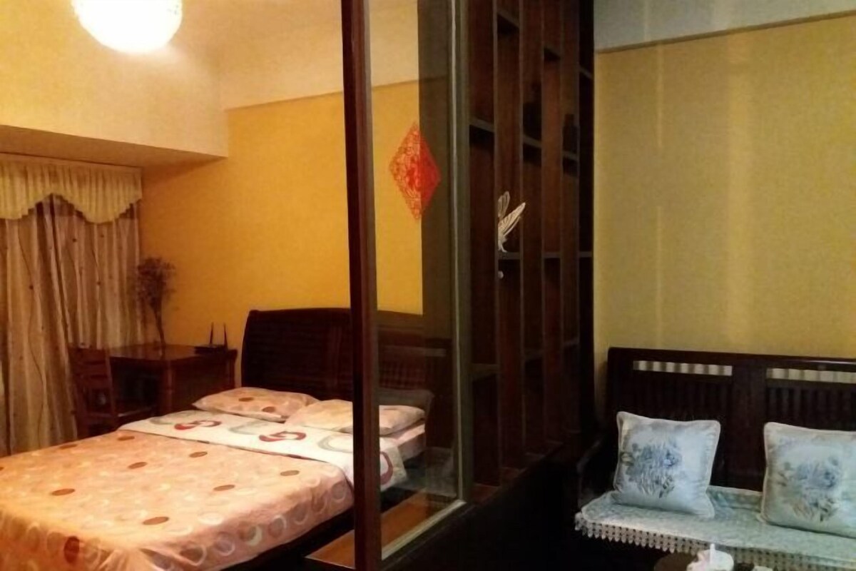 A hotel room with a bed, a sofa, a desk, and a window with curtains.