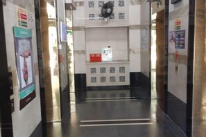 A hallway with a reception desk, a fan, and informational posters on the walls. - Shenzhen Four Seasons Family Apartment (Shenzhen)