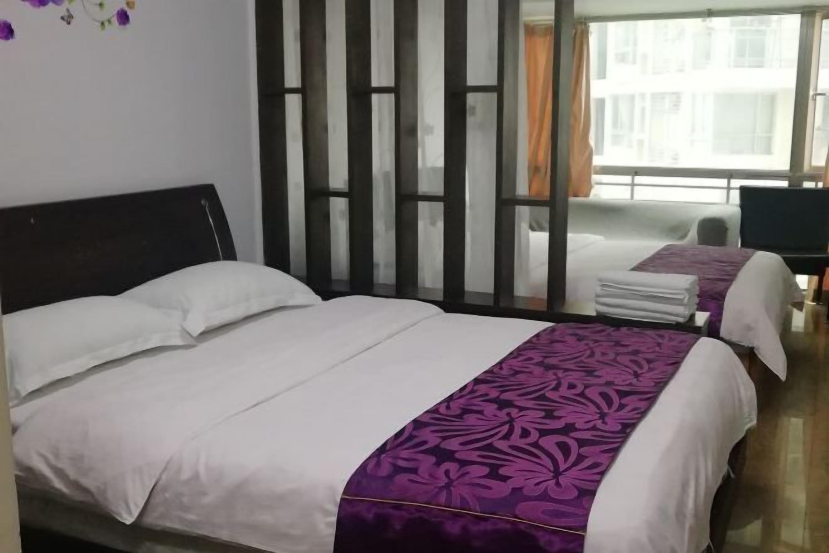 A hotel room with two beds, a large window, and a view of buildings outside.