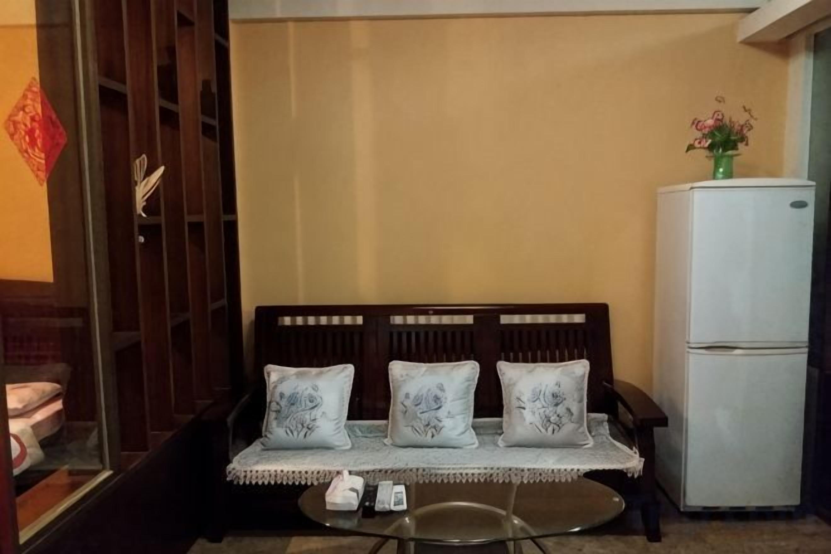 A room with a sofa, a small table, and a refrigerator.