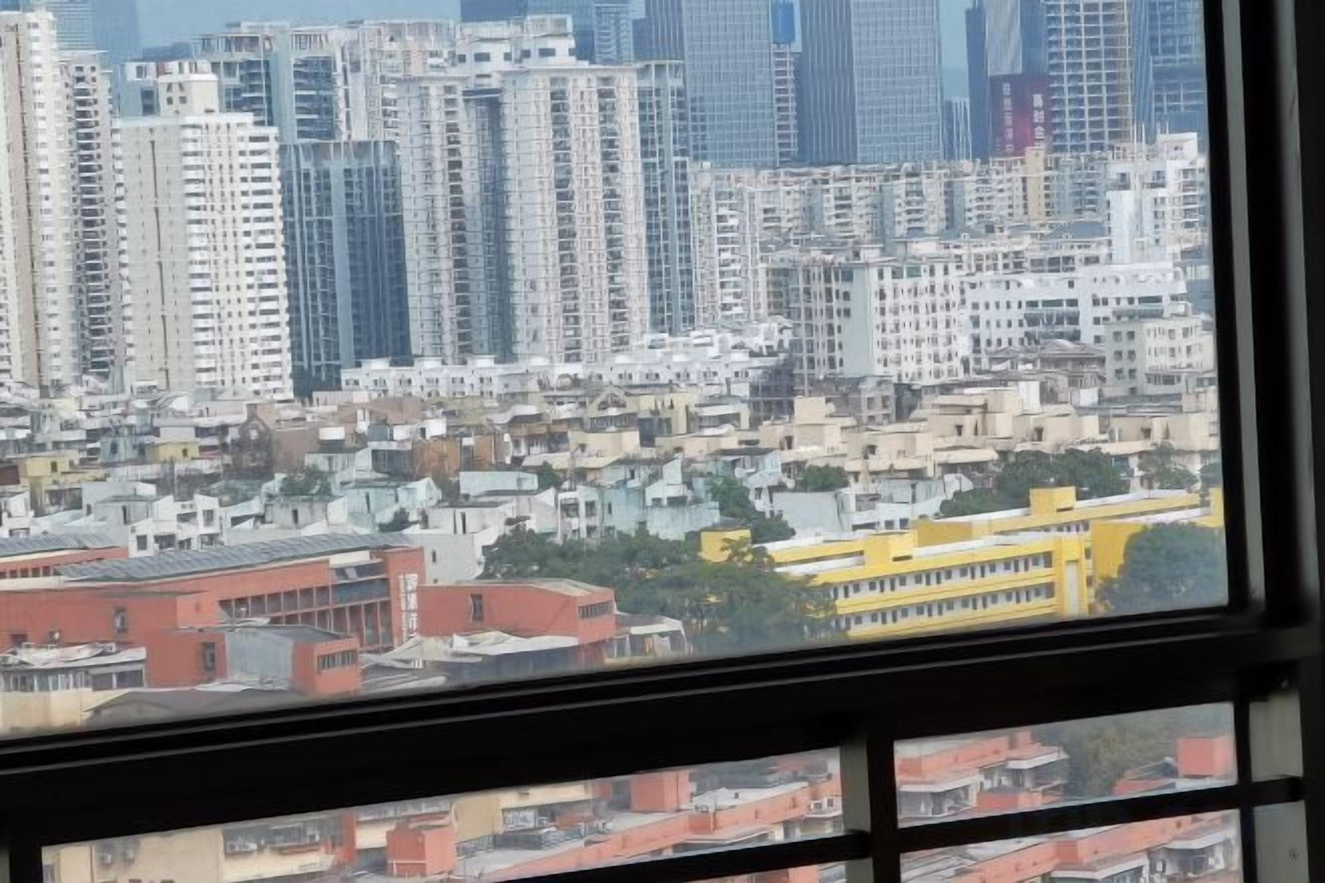 A cityscape view from a window, featuring high-rise buildings and a yellow bus in the foreground.