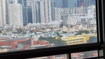 A cityscape view from a window, featuring high-rise buildings and a yellow bus in the foreground.