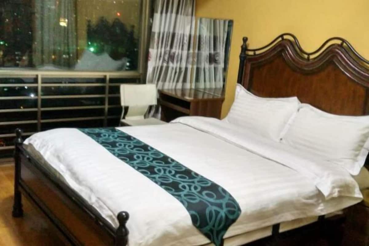 A bed with a patterned bedspread, a wooden headboard, and a nightstand with a lamp.