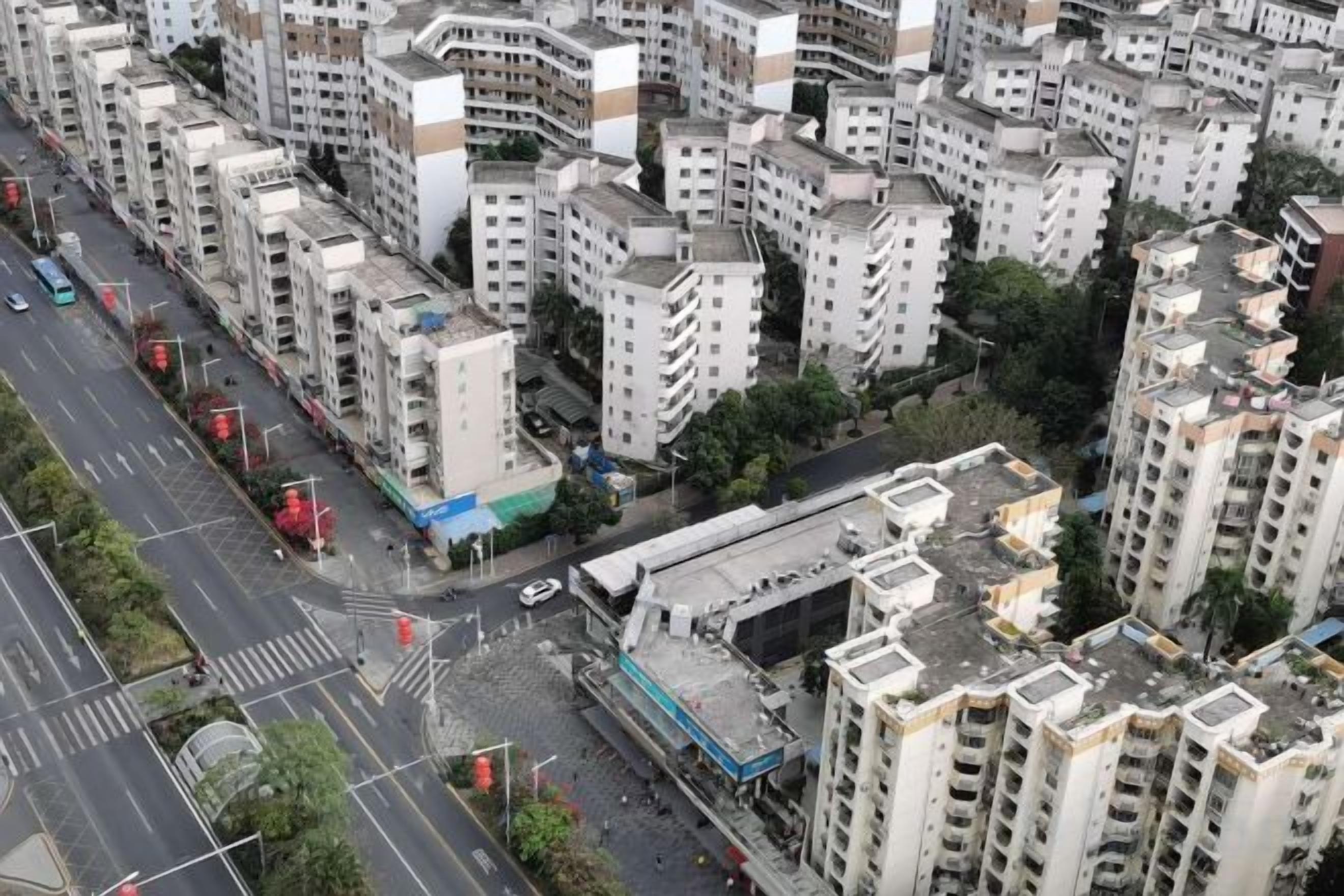 A high-rise residential building with multiple balconies, a central courtyard, and a street with traffic lights.