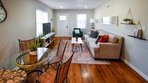 A living room with a glass dining table, two chairs, a sofa, a coffee table, and a TV. - ★ Cozy Escape★ Central Home ★ Plaza KC (Kansas City)
