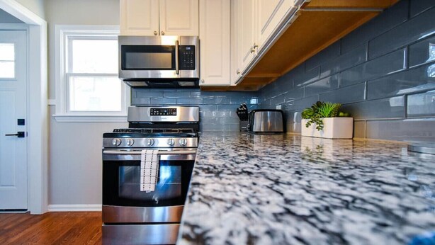 A kitchen with stainless steel appliances, a granite countertop, and a wooden floor. - ★ Cozy Escape★ Central Home ★ Plaza KC (Kansas City)