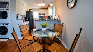 A compact kitchen with modern appliances, a dining area with wicker chairs, and a round glass table. - ★ Cozy Escape★ Central Home ★ Plaza KC (Kansas City)