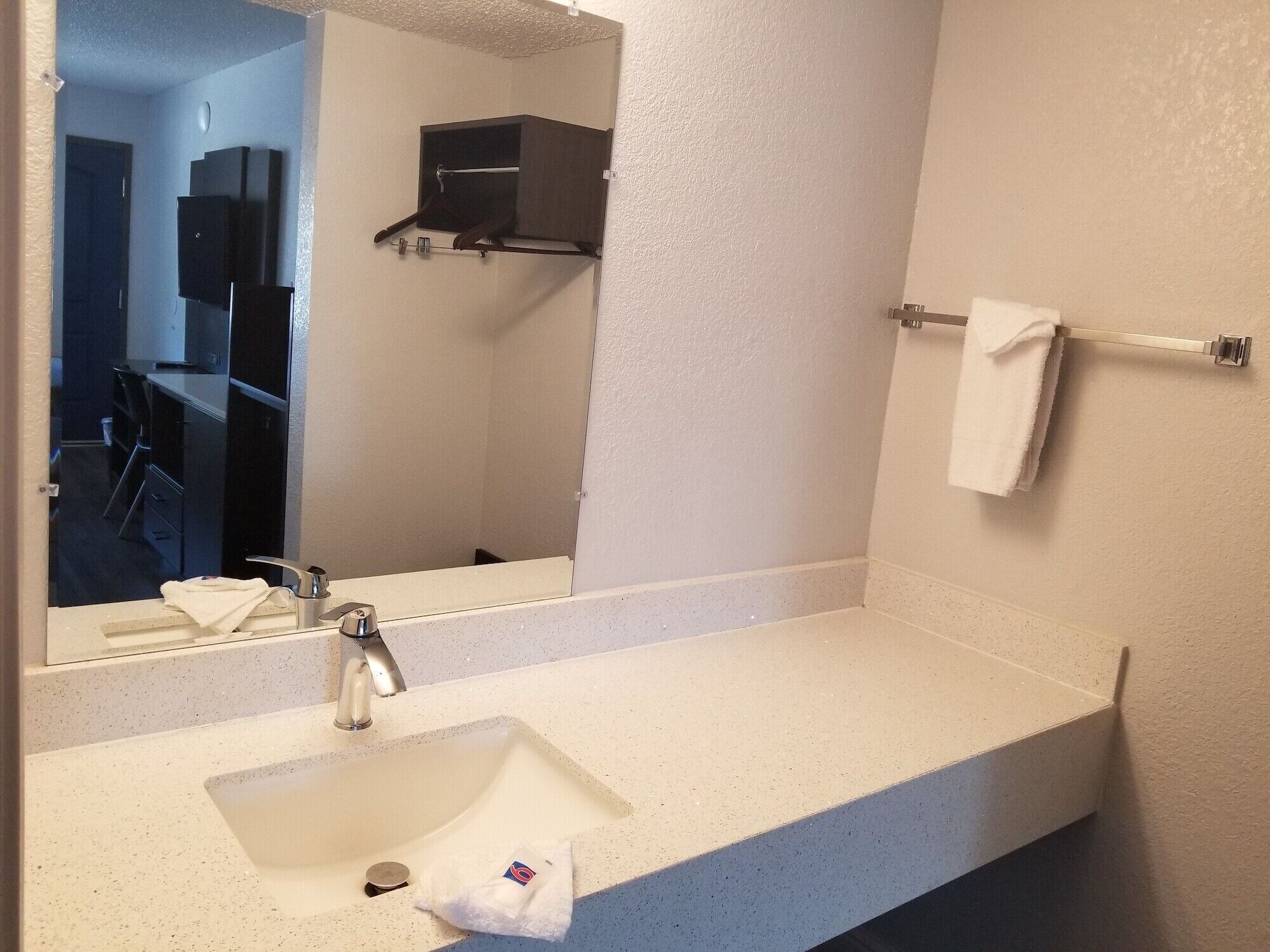 Un baño con lavamanos blanco, un espejo y un perchero para toallas.