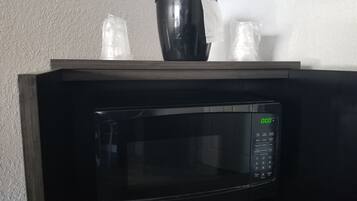 A black microwave oven with a digital display and control panel, placed on a wooden countertop.