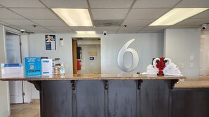 A reception desk with a large number '6' sign, a glass display case, and a black mat on the floor. - Motel 6 Sacramento, CA - Natomas & SMF Airport (Sacramento)