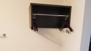 A corner room with a dark wooden bench, a wall-mounted shelf, and a white wall. - Motel 6 Sacramento, CA - Natomas & SMF Airport (Sacramento)