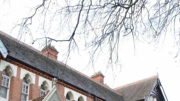 A large, historic building with a symmetrical facade, arched windows, and a prominent entrance.