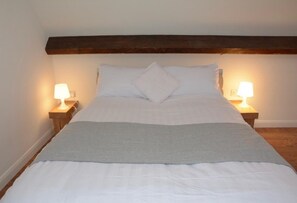 A bed with a wooden headboard, two bedside lamps, and a grey throw blanket. - Immaculate 1-bed Apartment in Birmingham (Birmingham)
