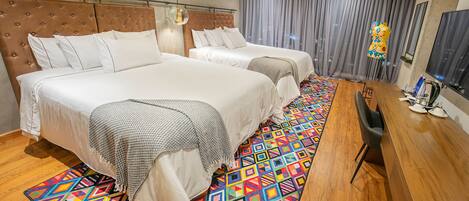A hotel room with two beds, a wooden desk, and a colorful rug.