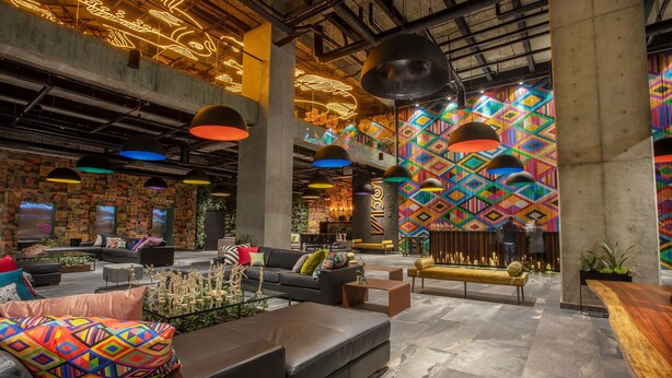 A spacious lobby with modern furniture, colorful geometric wall art, and industrial lighting. - Hotel V1501 (San Juan de Pasto)