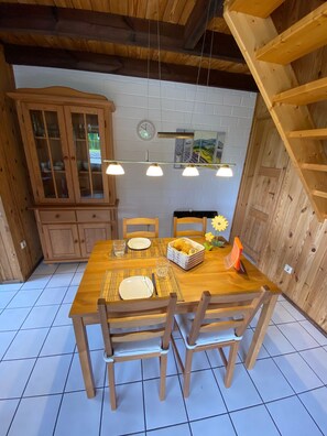 A wooden dining table with four chairs, a buffet, and a clock on the wall.