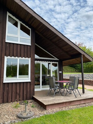 Een modern huis met een overdekte patio, grote ramen en een verzorgde tuin.