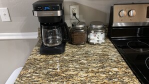 Une cuisine équipée d’une machine à café, de deux bocaux et d’une cuisinière.