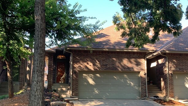Une maison d’habitation avec une façade en briques, un garage et une allée.