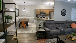 Un salon moderne avec un canapé gris, une table basse et un coin repas comprenant une table et des chaises.