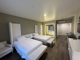 Una habitación de hotel con dos camas, un sofá, un escritorio y una televisión.