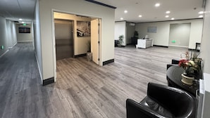 A spacious reception area with a modern design, featuring a reception desk, seating area, and a door leading to another room. - Aspire Inn & Suites Orange (Orange)
