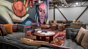 Una sala moderna con un mural grande, asientos cómodos y una mesa de centro.