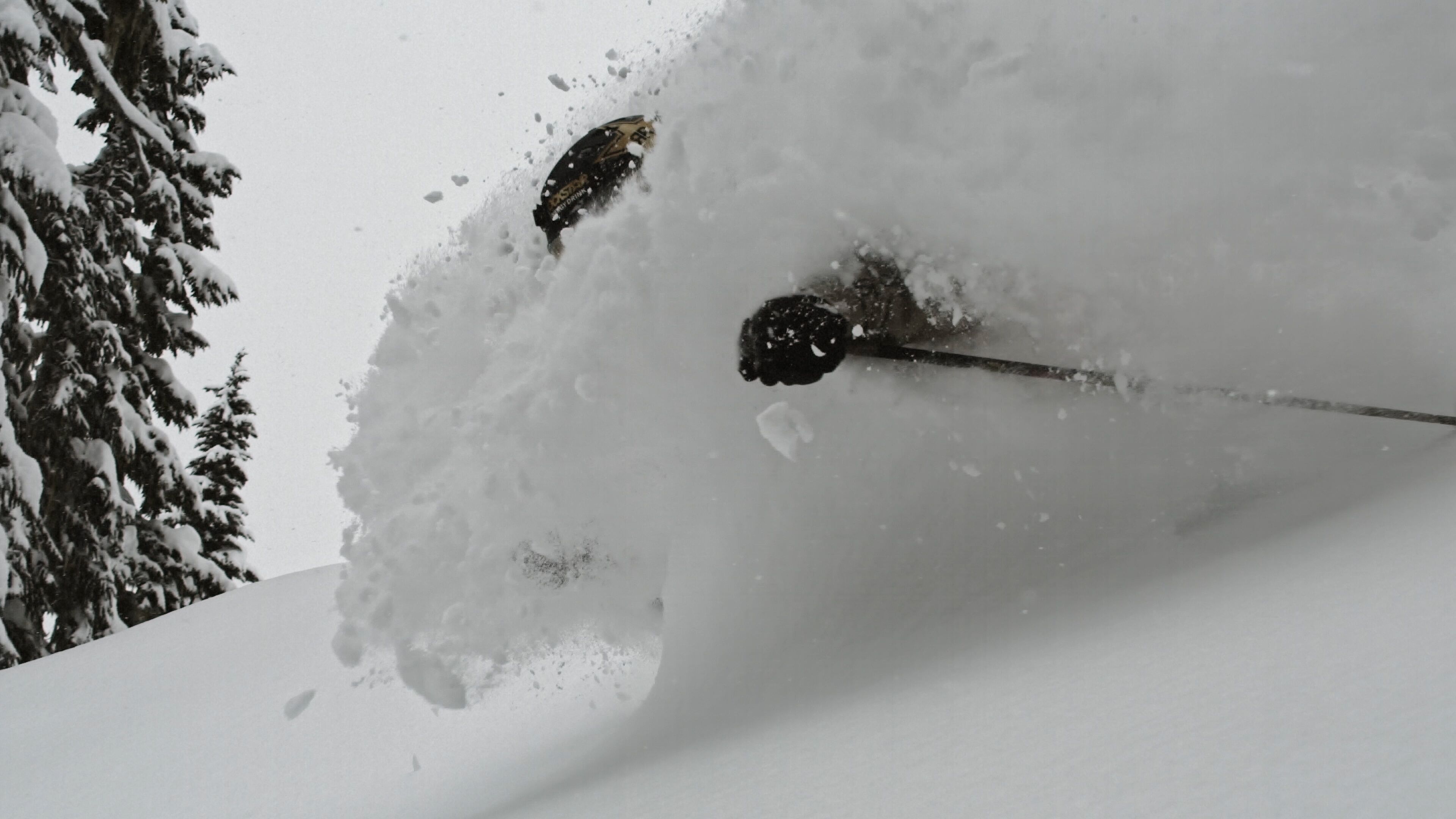 Pendiente nevada con un bastón de esquí y un par de esquíes parcialmente cubiertos de nieve.