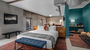 Un dormitorio moderno con una cama grande, un banco, un escritorio y un sofá.