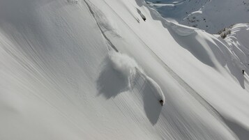 Ein mit Schnee bedeckter Hang mit einer Skipiste.