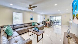 A spacious living room with a sectional sofa, a dining area, and a ceiling fan. - Luxury 5BR/3BA Villa Walk to  Hollywood Beach (Hollywood)