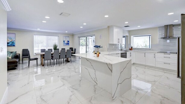 A modern kitchen with white marble countertops, a central island, and recessed ceiling lighting. - Luxury 5BR/3BA Villa Walk to  Hollywood Beach (Hollywood)