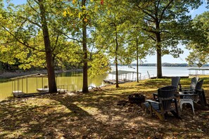 Un camping junto al lago con muelle, sillas y mesa de picnic.