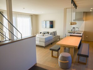 A modern living room with a sofa, a coffee table, and a TV mounted on the wall.