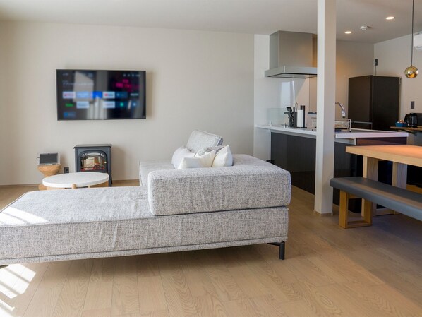 A modern living room with a grey sofa, a small round table, and a TV mounted on the wall.