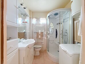 A compact bathroom with a sink, toilet, and shower.