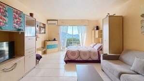 Een ruime, goed verlichte kamer met een bed, een bank, een televisie en een bureau.