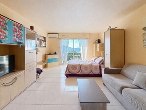 A well-lit, spacious room with a bed, a sofa, a TV, and a desk. - Exceptional view of the sunsets.  (Grosseto-Prugna)