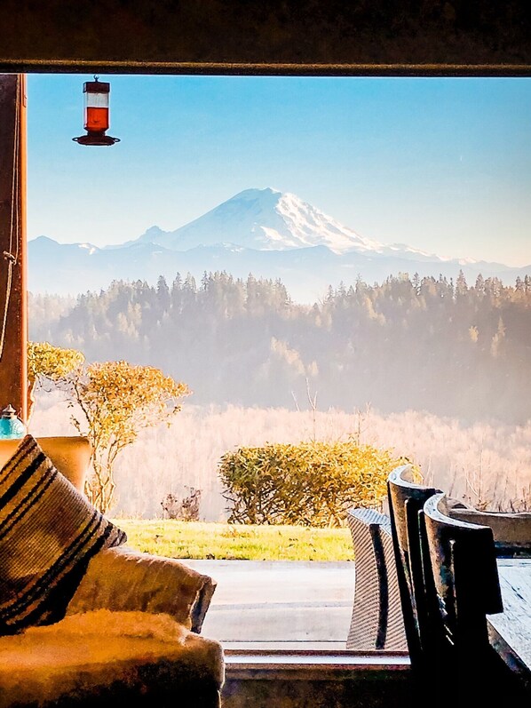 A room with a view of a mountain, a lamp, and a table with chairs.