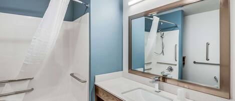 Une salle de bain moderne avec une baignoire, un grand miroir et un meuble-lavabo.