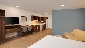 Une chambre d’hôtel compacte comprenant un coin cuisine, un lit, une télévision et un espace salon.