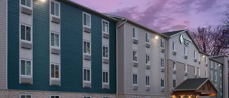 A multi-story hotel with a stone facade and a sign for 'Woodspring Suites'.