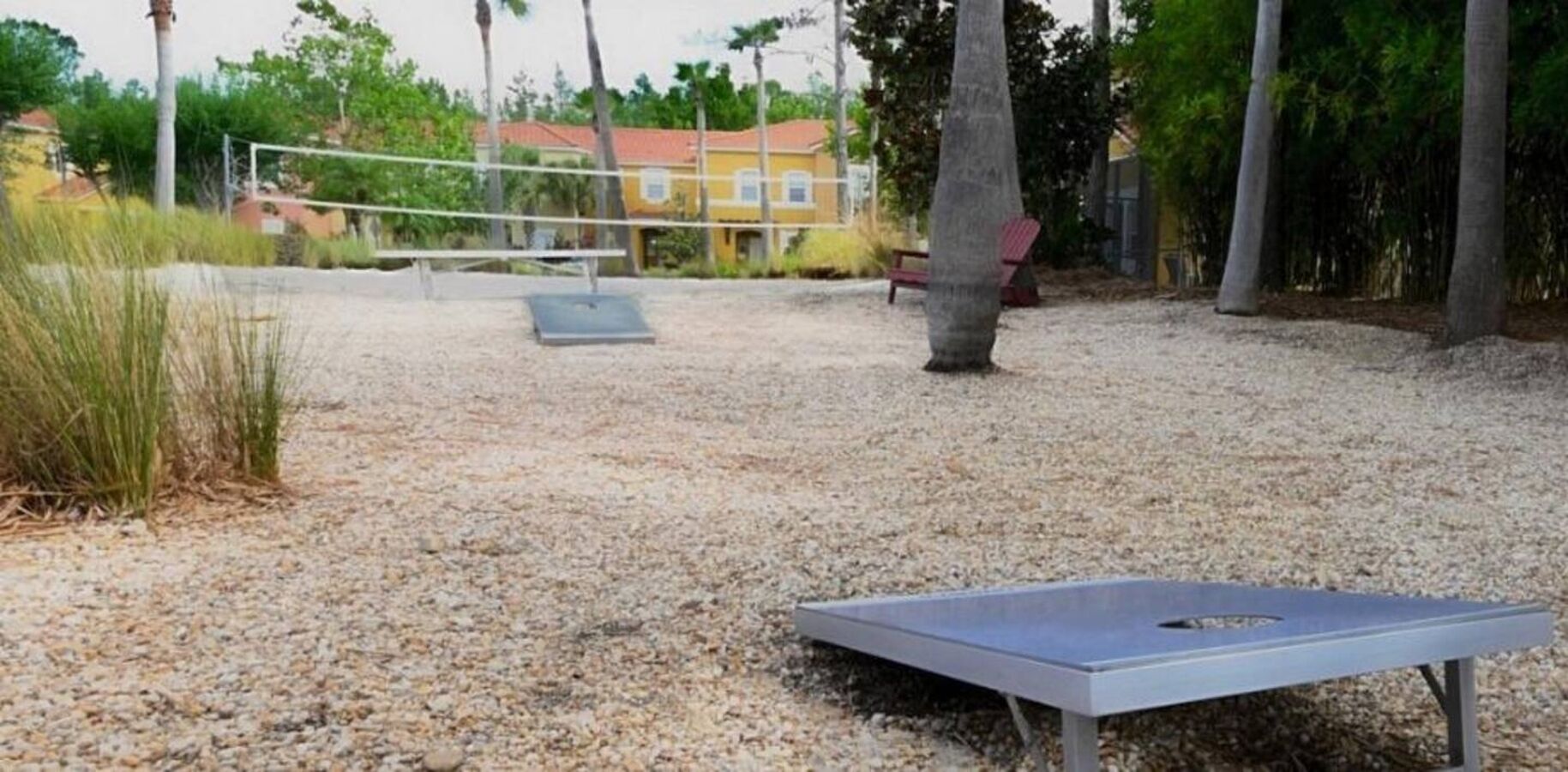 Un espacio exterior con mesa de ping pong, red de voleibol y un banco.